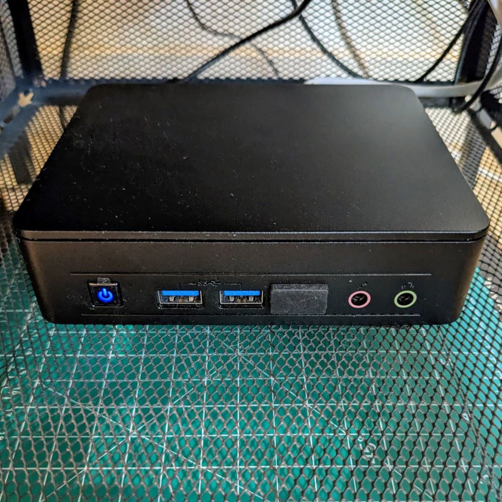 A small dusty server in a wire drawer with some cables in the background.